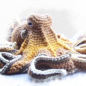 May include: A crocheted octopus plush toy with brown, yellow, and white yarn. The octopus has eight tentacles and a round head with two eyes.