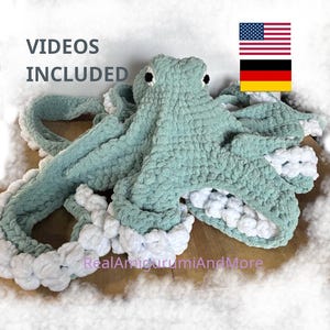 Puede incluir: Un gran pulpo de ganchillo hecho a mano en tonos turquesa y blanco. El pulpo tiene un aspecto texturizado y afelpado con tentáculos detallados y un ribete blanco contrastante. El texto "VIDEOS INCLUDED" es visible. Las banderas estadounidense y alemana también son visibles.