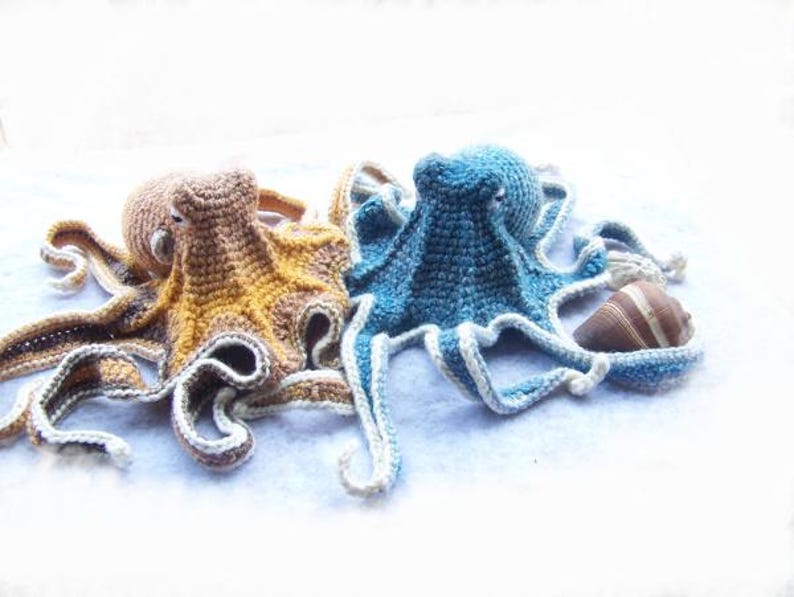 May include: Two crocheted octopus plushies, one blue and one brown, with a brown seashell.