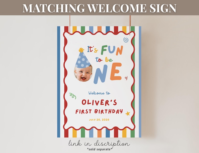 K&ouml;nnte beinhalten: Ein farbenfrohes Willkommensschild zum Geburtstag mit dem Text "It's FUN to be ONE" und einem Foto eines Babys mit Partyhut. Das Schild ist mit einem roten, gewellten Rand und vertikalen Streifen in verschiedenen Farben verziert. Es lautet "Welcome to OLIVER'S FIRST BIRTHDAY JULY 26, 2026."
