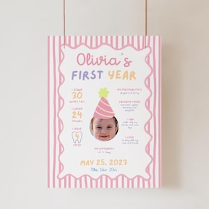 May include: A colorful poster celebrating a baby's first year, featuring a photo of the baby wearing a party hat. The poster includes the baby's height (30 inches), weight (24 pounds), and other details, with the text "Olivia's FIRST YEAR".