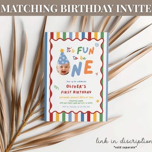 K&ouml;nnte beinhalten: Eine farbenfrohe Geburtstagseinladung mit dem Text "It's FUN to be ONE". Die Einladung zeigt ein Foto eines Babys mit Partyhut und enth&auml;lt Details f&uuml;r Olivers ersten Geburtstag. Das Design umfasst einen gestreiften Rand und dekorative Elemente.