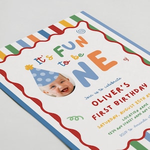 May include: A colorful birthday invitation with the text "It's FUN to be ONE." The invitation features a photo of a baby wearing a party hat. The invitation includes the text "OLIVER'S FIRST BIRTHDAY" and event details.