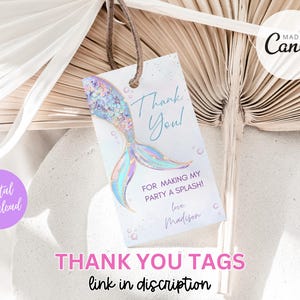 May include: A thank you tag with a mermaid tail illustration. The tag is light blue with pink and purple accents. The text on the tag reads "Thank You! For making my party a splash! Love, Madison".