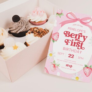Puede incluir: Una invitaci&oacute;n de cumplea&ntilde;os rosa con un dise&ntilde;o de fresas y margaritas. La invitaci&oacute;n dice "Join us for Penelope's Berry First Birthday, Sept 22, 3PM".