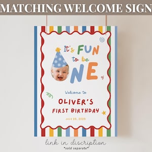 May include: A colorful birthday welcome sign with the text "It's FUN to be ONE" and a photo of a baby wearing a party hat. The sign includes the name "Oliver" and the date July 26, 2026. The sign has a red, white, and blue border.