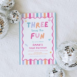 May include: A colorful birthday invitation with the text "THREE times the FUN" in playful lettering. The invitation features a pink scalloped border and vertical stripes in pastel colors. Silver disco balls surround the invitation.
