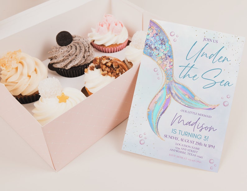 May include: A pastel blue and purple mermaid tail with gold glitter accents on a light blue background with white bubbles. The text "Join us Under the Sea" is written in a blue script font. The text "Our Little Mermaid Madison is turning 3!" is written in a black font. The text "Sunday, August 25th at 3PM" is written in a black font. The text "Location Name Any Street Anywhere, Texas" is written in a black font.