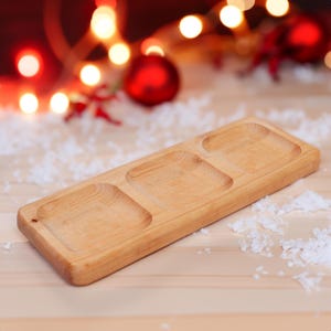 May include: A wooden serving tray with three separate compartments. The tray is made of light brown wood and has a smooth, polished finish.