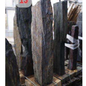 May include: A collection of rectangular, natural stone pillars. The central pillar is a mix of brown, gray, and black hues, with dimensions of 126x32x16 cm (approximately 49.6x12.6x6.3 inches). The number "13" is visible in a red circle.