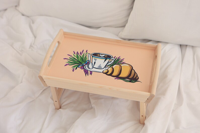 Klappbares Holztablett mit großem Bienenmotiv auf einer weißen Bettdecke, geeignet als Frühstücks- oder Betttablett.