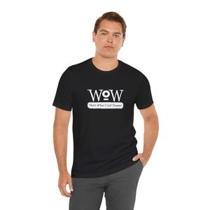 Może przedstawiać: Czarny t-shirt z krótkim rękawem z białym napisem "WOW" stylizowaną czcionką oraz frazą "That's What I Call Trauma!" nadrukowaną na biało poniżej w prostokątnej ramce. Wzór jest wyśrodkowany na wysokości klatki piersiowej.