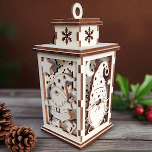 Könnte beinhalten: Eine lasergeschnittene Weihnachtslaterne aus Holz mit Wichtelfiguren, Sternen und Mondmotiven. Die Laterne hat einen quadratischen Boden, eine Aufhängeschlaufe und dunkelbraune Kanten. Der Text auf dem Bild lautet Laser Cut File - Christmas Lantern und 4 mm.