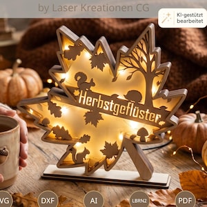 Könnte beinhalten: Eine lasergeschnittene Ahornblatt-Dekoration aus Holz mit integrierter warmer LED-Beleuchtung, filigranen Ausschnitten von einem Eichhörnchen, einem Igel und Bäumen sowie dem eingravierten Schriftzug "Herbstgeflüster" auf einem rechteckigen Sockel.