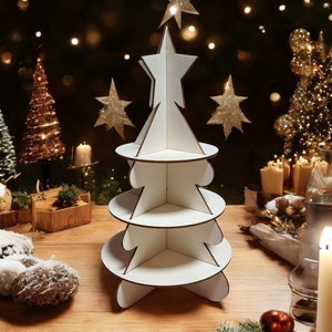 Könnte beinhalten: Ein weißer Papp-Weihnachtsbaumständer mit vier Ebenen. Der Baum ist mit einem Stern oben verziert und von Weihnachtslichtern und Dekorationen umgeben.