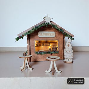 May include: A wooden miniature Gl&uuml;hwein stall featuring a brown structure with a star topper, green garland, and internal lights. The set includes two small round tables with light-colored legs and a flat-topped gnome figure standing to the right.
