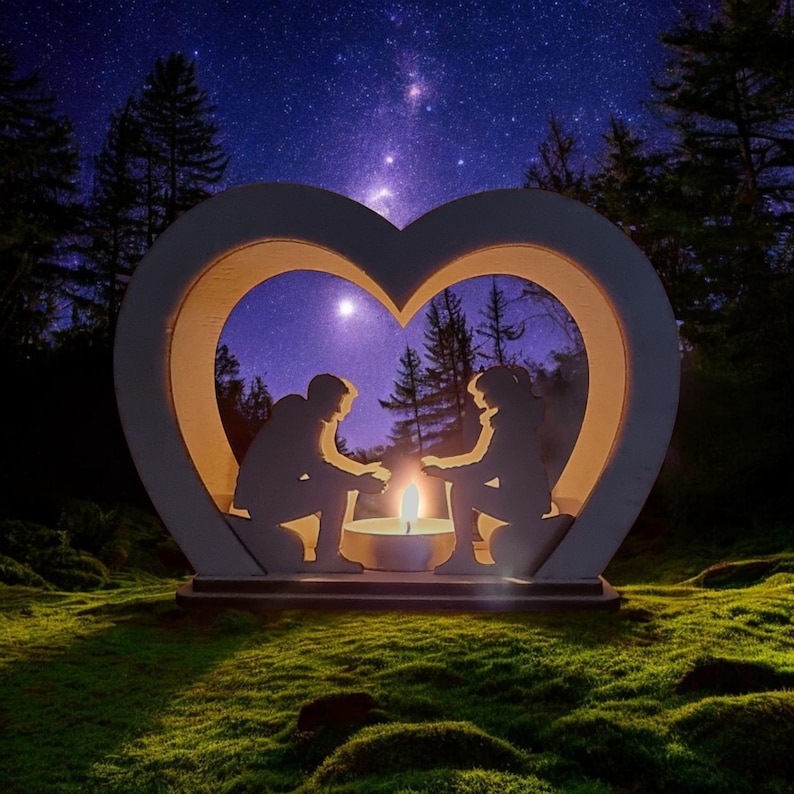 May include: Two silhouettes of people holding hands inside a white heart-shaped frame. The frame is illuminated from within, casting a warm glow. The background is a starry night sky.