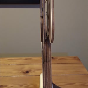 K&ouml;nnte beinhalten: Ein dekoratives Holzst&uuml;ck mit hellem Sockel und dunkelbrauner, vertikaler Struktur. Das St&uuml;ck hat ein geschichtetes Design mit einem hellen Element in der Mitte. Das Holz hat eine nat&uuml;rliche Maserung und das St&uuml;ck steht auf einer Holzoberfl&auml;che.