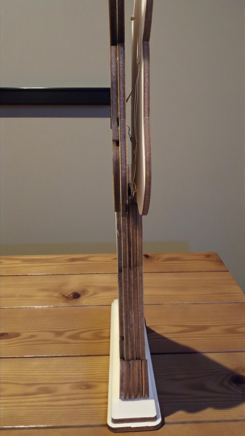 K&ouml;nnte beinhalten: Ein dekoratives Holzst&uuml;ck mit hellem Sockel und dunkelbrauner, vertikaler Struktur. Das St&uuml;ck hat ein geschichtetes Design mit einem hellen Element in der Mitte. Das Holz hat eine nat&uuml;rliche Maserung und das St&uuml;ck steht auf einer Holzoberfl&auml;che.