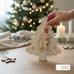 May include: A light-colored wooden Christmas tree ornament featuring a cutout gingerbread man figure at the center and the text "Frohe Weihnachten" engraved on the surface. The tree is topped with a star and includes circular cutouts.