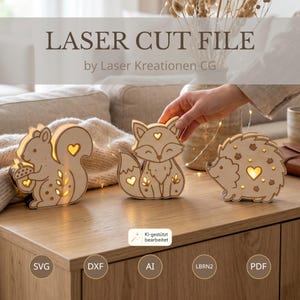 Può includere: Tre figure di animali in legno chiaro che includono uno scoiattolo con una ghianda, una volpe e un riccio. Ogni figura presenta ritagli a forma di cuore e foglie che emettono una luce calda. Il testo recita LASER CUT FILE by Laser Kreationen CG.