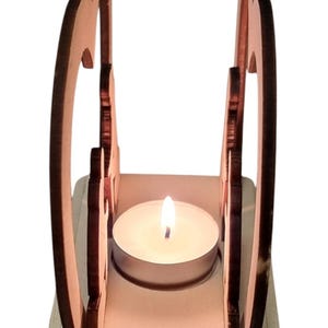 May include: A wooden candle holder shaped like two hearts with a tea light candle inside. The candle holder is made of light brown wood and has a natural finish.