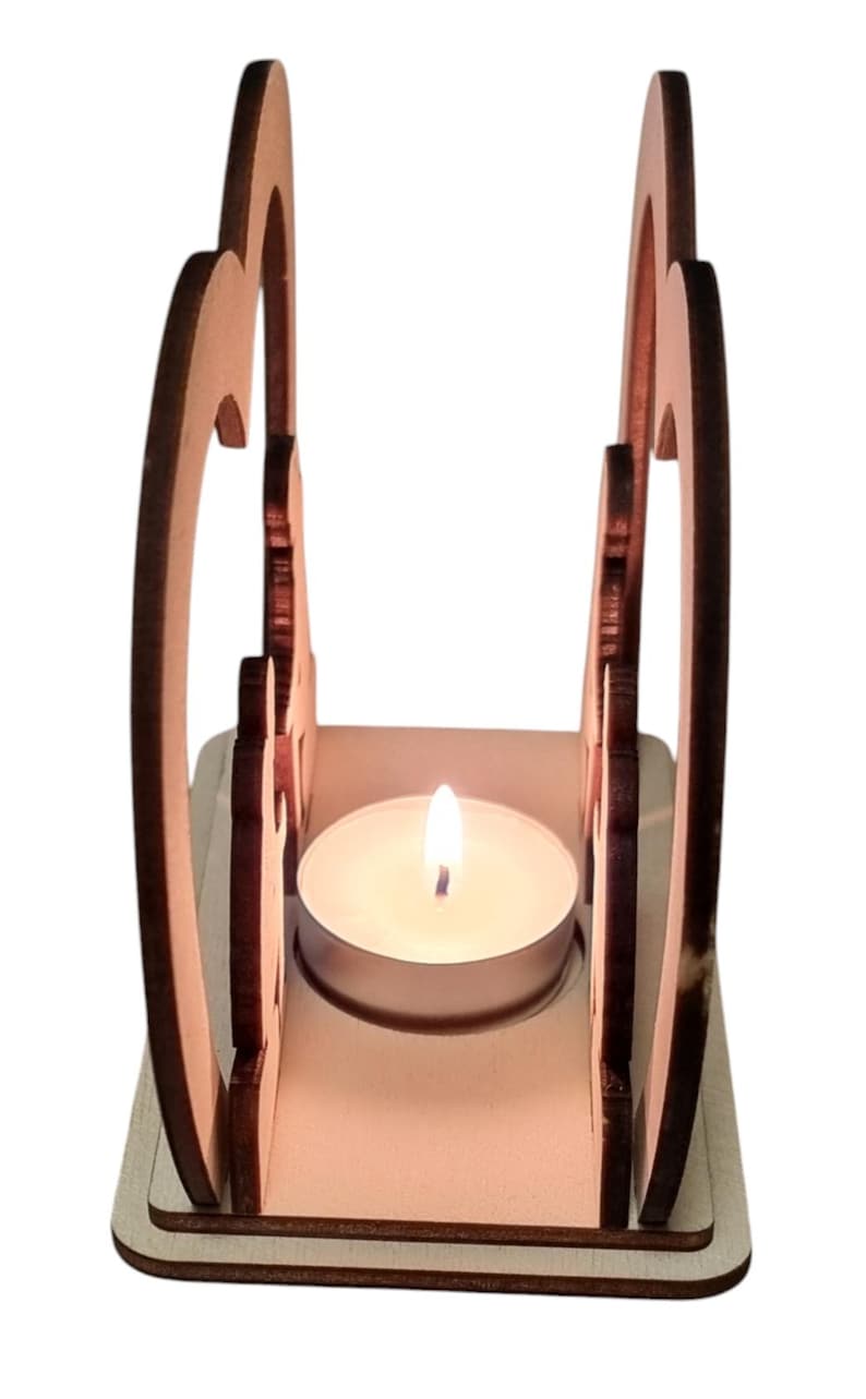 May include: A wooden candle holder shaped like two hearts with a tea light candle inside. The candle holder is made of light brown wood and has a natural finish.