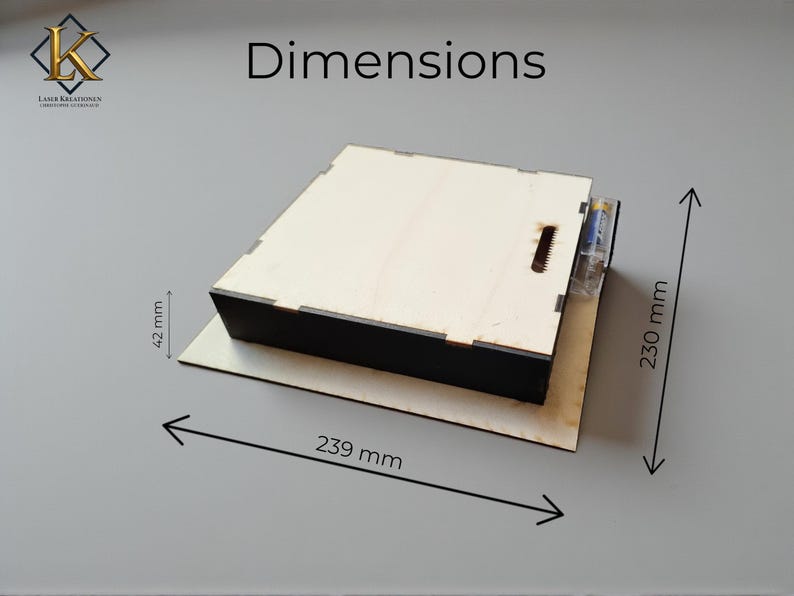 May include: A wooden box with a black base and a light-colored top. The dimensions are 9.4 inches long, 9 inches wide, and 1.7 inches high. The box has a slot on the top and a clear plastic tube attached to the side.