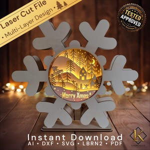 Könnte beinhalten: Ein mehrschichtiges Laser-Cut-Schneeflocken-Design mit einer Winterszene im Inneren. Das Design enthält den Text "Merry Xmas" und "Instant Download". Die Schneeflocke ist aus hellem Holz gefertigt.