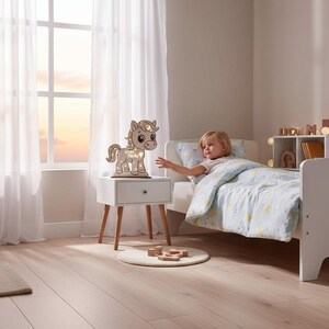 K&ouml;nnte beinhalten: Ein h&ouml;lzernes pferdef&ouml;rmiges Nachtlicht mit Stern- und Monddesign steht auf einem wei&szlig;en Nachttisch in einem Kinderzimmer. Das Zimmer verf&uuml;gt &uuml;ber ein Bett mit einer blau-wei&szlig; gemusterten Bettdecke, ein Fenster mit transparenten Vorh&auml;ngen und Holzspielzeug.