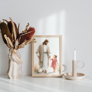May include: A framed print of a painting depicting Jesus walking with a young girl. The print is on a white shelf with a vase of dried flowers and a candle holder.