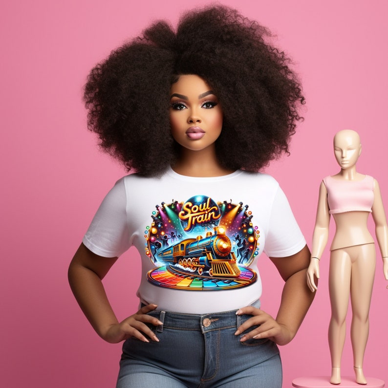 May include: A woman wearing a white t-shirt with a colorful "Soul Train" graphic featuring a train, lights, and a rainbow-colored platform. She is wearing blue jeans. A mannequin is standing to her right. The background is pink.