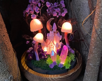 May include: A miniature fairy house with a pink and white exterior, surrounded by purple flowers, mushrooms, and crystals. The house is lit up with warm white lights, creating a magical and whimsical scene.