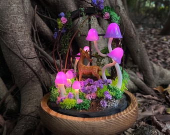 May include: A miniature woodland scene with a deer figurine and glowing purple mushrooms in a wooden base. The mushrooms are arranged around the deer and are illuminated with a soft purple light.