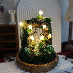 May include: A miniature forest scene with a wooden base and a deer figurine. The scene is lit by small, white, mushroom-shaped lights.