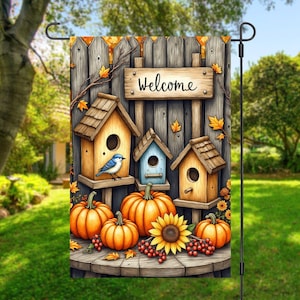 Puede incluir: Bandera de jardín decorativa con un fondo de valla de madera y un letrero que dice "Welcome". La bandera muestra casas para pájaros, calabazas, un girasol y un pájaro azul. El diseño tiene un tema otoñal.