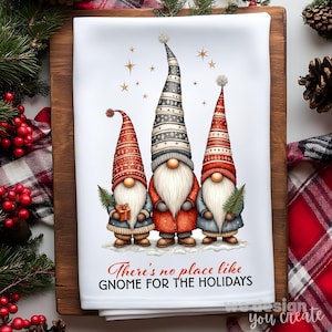 K&ouml;nnte beinhalten: Wei&szlig;es K&uuml;chentuch mit drei Wichteln mit langen wei&szlig;en B&auml;rten und hohen, gemusterten H&uuml;ten in Rot, Grau und Schwarz. Die Wichtel tragen M&auml;ntel und halten Geschenke und einen kleinen Baum. Der Text lautet: "There's no place like gnome for the holidays."