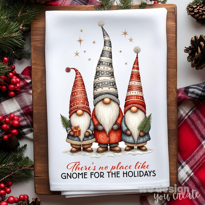 K&ouml;nnte beinhalten: Wei&szlig;es K&uuml;chentuch mit drei Wichteln mit langen wei&szlig;en B&auml;rten und hohen, gemusterten H&uuml;ten in Rot, Grau und Schwarz. Die Wichtel tragen M&auml;ntel und halten Geschenke und einen kleinen Baum. Der Text lautet: "There's no place like gnome for the holidays."