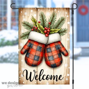 May include: A decorative garden flag featuring a pair of red and black plaid mittens with white trim, topped with holly and pine. The word "Welcome" is written in black script on a wooden background. Snowflakes are scattered around the design.