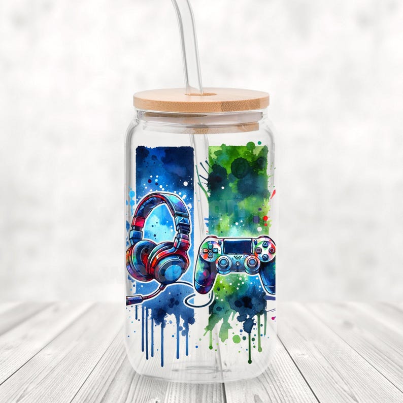 May include: A clear glass water bottle with a bamboo lid and a straw. The bottle has a colorful design with a video game controller and headphones.