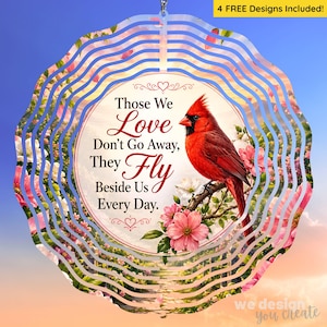May include: A circular wind spinner featuring a red cardinal perched on a branch with pink flowers. The center text reads: Those We Love Don't Go Away, They Fly Beside Us Every Day. A yellow banner at the top states: 4 FREE DESIGNS Included!
