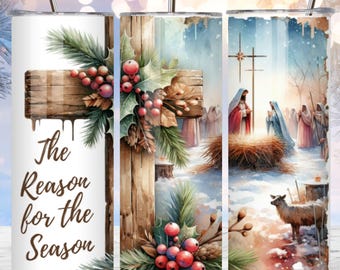May include: A white tumbler with a Christmas scene featuring a wooden cross, holly, and the text "The Reason for the Season". The scene is set in a snowy winter landscape with a manger and a shepherd.