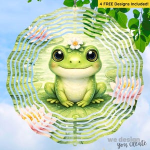 Peut inclure: Un mobile éolien en métal fantaisiste avec un motif de grenouille verte souriante, orné d'une fleur blanche et d'un nénuphar. Le design comprend des nénuphars roses et jaunes et le texte "4 FREE Designs Included!" et "we design you create".