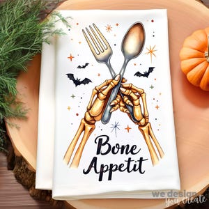 May include: White kitchen towel with a Halloween design. The towel features a skeleton holding a fork and spoon, with the words "Bone Appetit" in black script. Bats and stars are also included in the design.