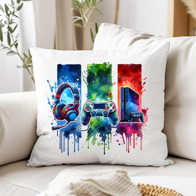 May include: A white pillow with a colorful watercolor design featuring a video game controller, headphones, and a game console. The design is in shades of blue, green, red, and yellow.