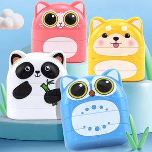 May include: Four colorful animal-shaped toys: a pink cat, yellow dog, white panda, and blue owl. Each toy has large, expressive eyes and a stacked design. The panda holds bamboo, and the dog has a pink blush.