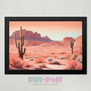 Puede incluir: Una impresión enmarcada de un paisaje desértico con dos cactus altos en primer plano y formaciones rocosas rojas en el fondo. El cielo es de un color naranja suave.