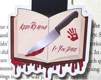 May include: A bookmark featuring an open book design with a knife and a bloody handprint. The text "KEEP READING IF YOU DARE" is displayed on the book. The bookmark is placed over a book's pages.
