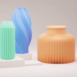 Peut inclure: Trois vases décoratifs de couleurs et de styles différents. Un vase bleu clair avec un motif en spirale, un vase vert clair avec des crêtes verticales et un vase orange clair avec des crêtes verticales.