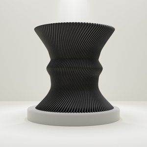 Op de afbeelding: Een zwarte, abstracte, sculpturale vaas met een golvend, geribbeld ontwerp. De vaas staat op een wit voetstuk.